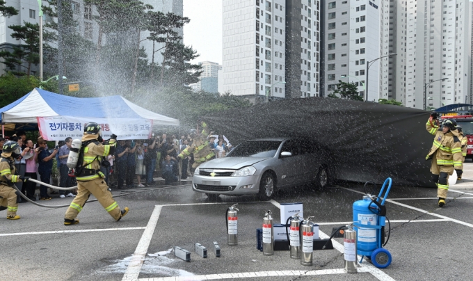 13일 인천시 연수구 송도 2동 행정복지센터 주차장에서 열린 전기자동차 화재대응 민·관 합동 교육에서 소방관들이 질식소화포와 전기차 수조탱크를 이용한 전기차 화재 진압 모의 시연을 하고 있다./사진 제공=중부일보