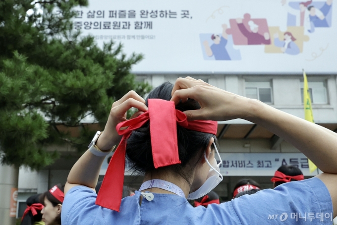 [서울=뉴시스] 최동준 기자 = 26일 서울 중구 국립중앙의료원 앞에서 총파업을 예고한 전국보건의료노조 조합원이 조속한 진료 정상화, 불법의료 근절과 업무 범위 명확화 등 촉구 선전전에 참석하며 머리띠를 두르고 있다. 2024.08.26. photocdj@newsis.com /사진=최동준