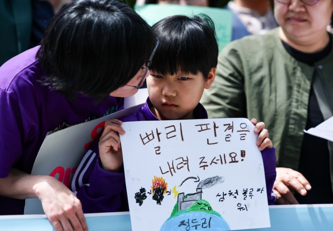 [서울=뉴시스] 김근수 기자 = 기후환경시민단체의 어린이 회원이 23일 서울 종로구 헌법재판소 정문 앞에서 한국 정부의 기후소송 첫 공개변론을 앞두고 열린 기자회견에서 기후 위기의 심각성을 알리는 손 피켓을 들고 있다. 2024.04.23./사진=뉴시스