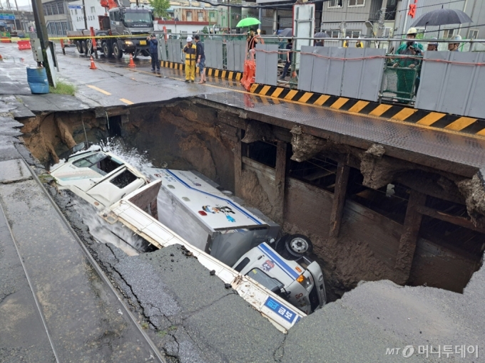  21일 오전 8시45분께 부산 사상구 한 도로에서 가로 10m, 세로 5m, 깊이 8m 가량의 대형 땅꺼짐 현상(싱크홀)이 발생해 도로에서 배수 지원을 하던 삼락119안전센터 배수 차량과 5톤 트럭이 빠져있다. /사진=부산소방재난본부 제공