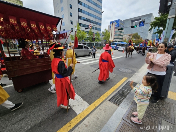 6일 오전 서울 용산구 한강대로 노들섬 방향 차로에서 정조대왕 능행차 재현 행사 참가자들이 행진하고 있다. 세종시에 사는 서규진씨(42·남)는 이날 딸 지윤양(4)과 아내와 행렬을 구경하러 서울에 왔다. 사진은 혜경궁홍씨를 향해 손을 흔드는 지윤양과 사진을 찍는 규진씨의 아내. /사진=정세진 기자 