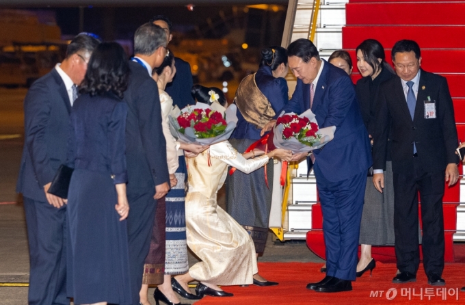 [비엔티안=뉴시스] 최진석 기자 = 아세안(ASEAN·동남아시아국가연합) 정상회의 참석차 라오스를 방문한 윤석열 대통령과 부인 김건희 여사가 9일(현지시각) 비엔티안 왓타이 국제공항에 도착해 1호기에서 내려 환영 인사로부터 꽃다발을 받고 있다. 2024.10.09. myjs@newsis.com /사진=최진석