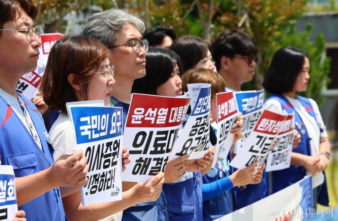 [서울=뉴시스] 김근수 기자 = 전국민주노동조합총연맹 공공운수노조 의료연대본부 조합원들이 14일 오후 서울 종로구 서울대학교 병원 앞에서 열린 윤석열 정부 의료대란 해결 촉구와 의사 집단 휴진을 규탄하는 기자회견에서 손피켓을 들고 서 있다. 2024.06.14. ks@newsis.com /사진=김근수