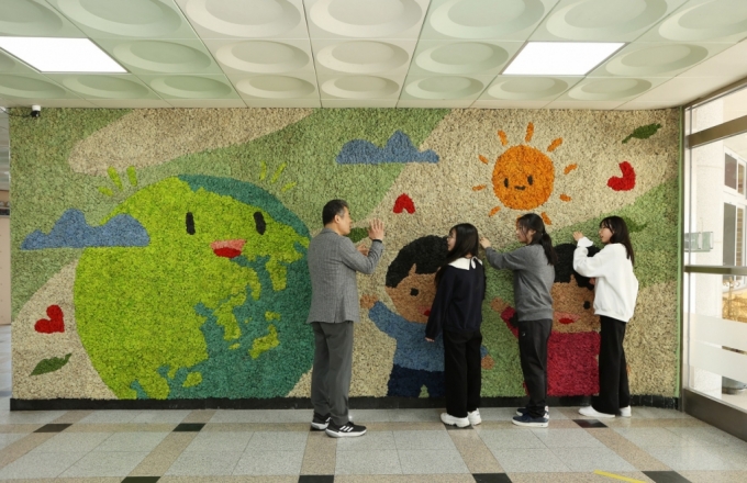 용인 나곡초등학교의 선생님과 아이들이 맑은학교 만들기를 통해 조성된 벽면녹화를 살펴보고_있다