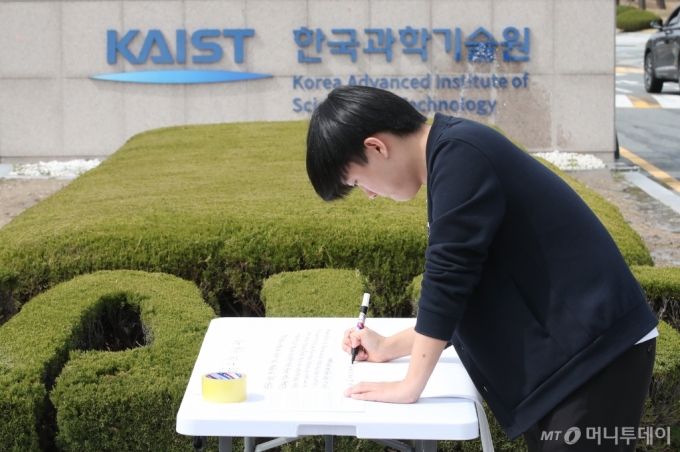 채동주 한국과학기술원(KAIST) 21학번 학생(학위수여식 R&D 예산 복원 요구 입틀막 강제퇴장에 대한 대학생·졸업생 대책위원회 공동대표)이 지난 4월 대전 유성구 KAIST 본원 정문 앞에서 전국의 이공계 학생에게 투표 참여를 호소하는 대자보를 작성하고 있다. /사진=뉴스1