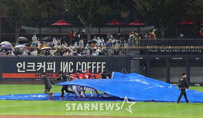 경기장 스태프들이 구장에 내린 비로 방수포를 덮고 있다. /사진=김진경 대기자