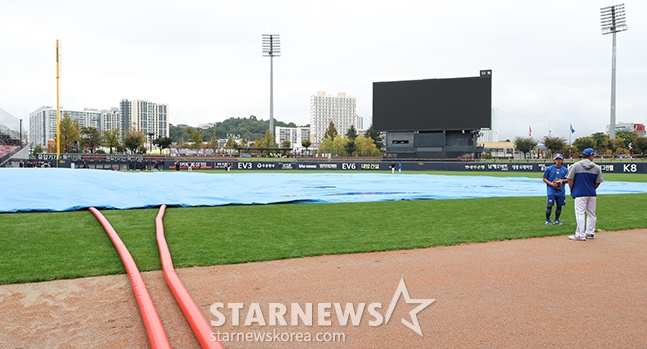 '2024 KBO 포스트시즌 한국시리즈 1차전' KIA-삼성전 서스펜디드 경기가 22일 광주-기아챔피언스필드에서 열렸다. 구단 관계자들이 비에 젖은 그라운드를 정비하는 가운데 KIA 선수들이 외야에서 훈련을 하고 있다. /사진=김진경 대기자