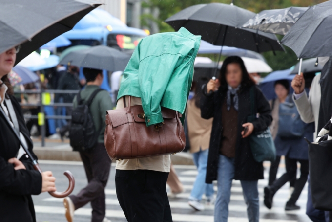 서울 광화문네거리에서 우산을 챙기지 못한 시민이 겉옷으로 비를 가리고 있다.  /사진=뉴스1