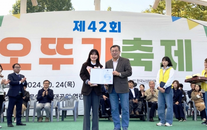 지난 24일 서울어린이대공원에서 개최된 뇌성마비인을 위한 문화예술축제 행사인 '오뚜기 축제'에서 한국뇌성마비복지회 김정우 회장이 유니클로 윤보람 서스테이너빌리티 매니저에게 보건복지부 장관 표창을 수여하는 모습/사진=유니클로