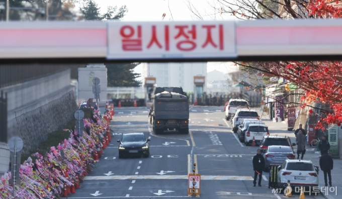 [서울=뉴시스] 최진석 = 윤석열 대통령 탄핵소추안이 국회에서 가결된 14일 서울 용산 한 주차장 차단기의 일시정지 문구 뒤로 대통령실 입구가 보이고 있다. 국회의장 명의의 탄핵소추 의결서 등본이 전달되면 곧바로 윤 대통령 직무는 정지된다. 2024.12.14. myjs@newsis.com /사진=최진석