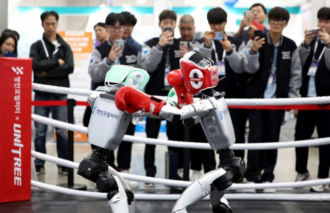 [대구=뉴시스] 이무열 기자 = 23일 대구 북구 엑스코에서 열린 미래혁신기술박람회(FIX 2025)에서 관람객들이 중국 로봇 기업 유니트리 로보틱스(Unitree Robotics)가 개발한 휴머노이드 로봇 &#039;G1&#039; 복싱 경기 시연을 보고 있다.  FIX 2025는 미래형 모빌리티와 로봇 산업의 융합을 주제로 25일 까지 엑스코 전관에서 진행된다. 2025.10.23