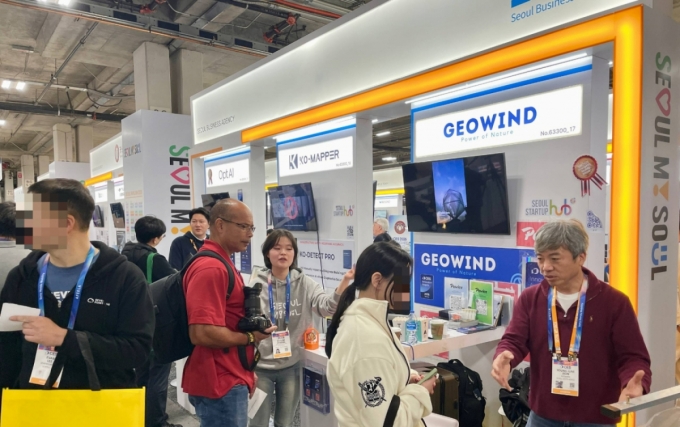 CES 2026 서울통합관에 참여한 옵트에이아이&middot;코매퍼&middot;지오윈드 관계자들이 방문객에게 회사를 소개하고 있다./사진=김성휘