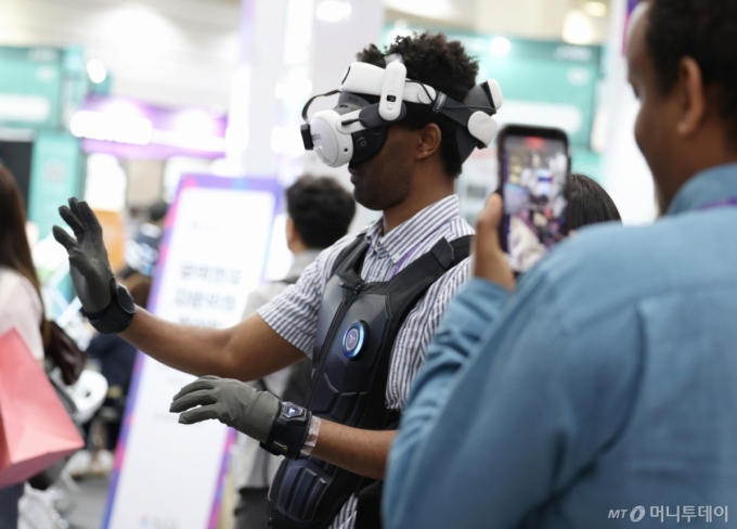 지난해 6월 26일 서울 삼성동 코엑스에서 막을 올린 글로벌 스타트업 전시회 '넥스트라이즈 2025'에서 한 외국인이 햅틱 웨어러블 기기를 착용한 채 VR 체험을 하고 있다. /사진=뉴스1