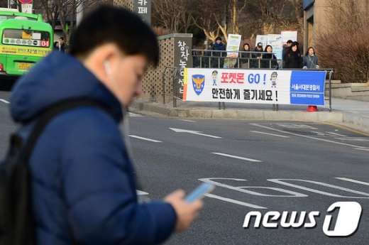 지난 2월 초 서울 서대문구 연세대학교 정문 앞 도로에 설치된 '포켓몬 고' 안전 관련 현수막 앞으로 한 시민이 핸드폰을 보며 걷고 있다. /사진=뉴스1.