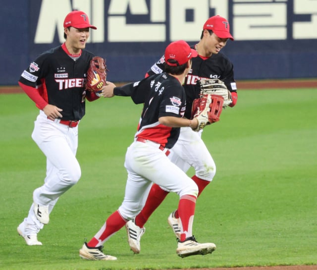 KIAタイガースの左翼手、朴ジェヒョン(右)が26日、大邱(テグ)の三星ライオンズパークで行われた三星ライオンズと2026新韓(シンハン)SOLKBOポストシーズンプレーオフ(PO)第1戦の7回裏、カン·ミンホの打球をダイビングキャッチしてイニングを終え、同僚たちの激励の中でダッグアウトに向かう。 /写真=キム·ジンギョン待機者