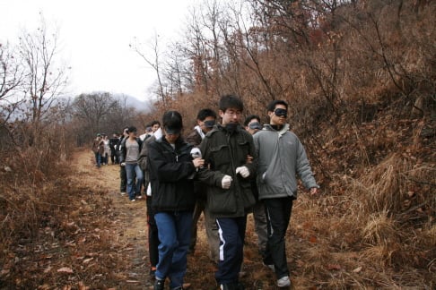 신영증권 신입사원들이 안대를 착용하고, 12km 트래킹을 하고 있다.