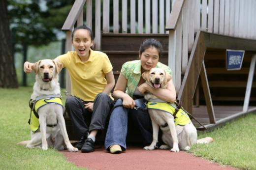 ↑삼성화재로부터 안내견을 기증받은 강신혜(왼쪽)씨와 김경민씨가 자신의 안내견인 '미담', '미래'와 포즈를 취하고 있다.