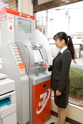한 관광객이 도쿄 시나가와구의 세븐일레븐 매장에 설치된 세븐뱅크 ATM에서 현금을 인출하고 있다.