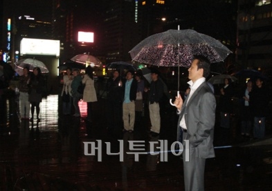 ↑봄비 우산속에서 라이브선율을 즐기는 관람객들