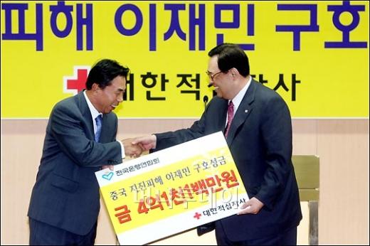 ↑전국은행연합회 회장 유지창(왼쪽)과 대한적십자사 총재 이세웅이 성금전달식을 하며 악수를 나누고 있다.