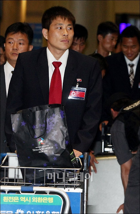 ↑북한축구대표팀 김영준이 동료들과 함께 입국하고 있다.