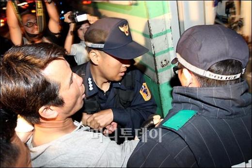 ↑22일 밤 서울 세종로사거리에서 경찰의 강제해산에 강력히 저항하던 촛불집회 참가자가 경찰들에게 연행되고 있다. ⓒ홍봉진 기자