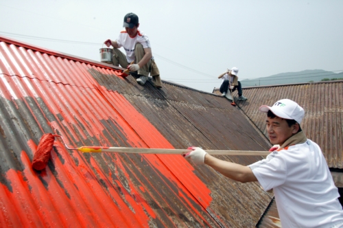 ▲KTF 임직원들이 23일 경기 김포 용강리 민통선마을에서 독거노인이 거주하는 주택의 도색작업을 하고 있다.