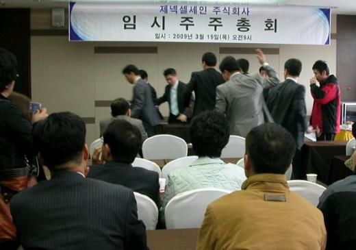 ▲김정출 제넥셀 대표가 19일 임시주총 도중 연회를 선언하고 일어나자 주주들이 못가게 막고 있다.