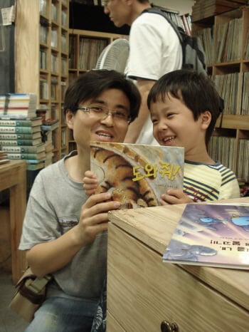 ↑ 지난해 6월21일 서울 광화문 '아름다운 헌책방'에서 열린 '머니투데이와 함께 하는 아름다운 토요일' 행사장에 아빠와 함께 서점을 찾은 어린이가 책을 고르고 웃고 있다. ⓒ이경숙기자