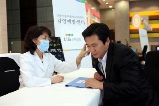 ↑LIG손해보험 직원이 출근 전 발열증상 여부를 체크하고 있다.