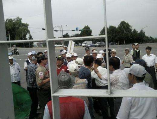 김 전 대통령 묘지 참배를 마치고 국립현충원을 나온 한 시민(가운에 빨간상의)이 대한민국 어버이연합회 회원에 둘러싸여 있는 모습. 출처: 미디어몽구