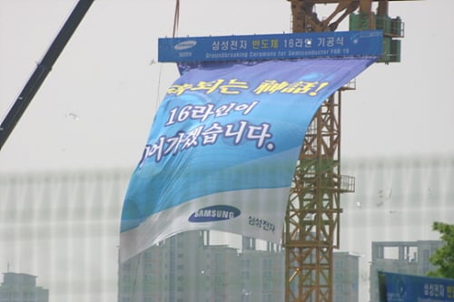 ↑이건희 삼성 회장이 참석한 가운데 17일 경기도 화성 반도체 사업장에서 열린 16라인 기공식에서 '계속되는 신화 16라인이 이어가겠습니다'라는 플랫카드가 휘날리고 있다.
