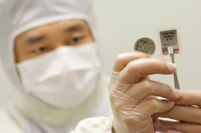 ↑한 연구원이 GS칼텍스의 박막전지를 들어 동전과 크기를 비교해보고 있다.