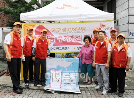 ↑ 이광석 SK건설 사회공헌 사무국장(왼쪽)과 임직원이 희망메이커 활동의 일환으로 주민에게 생필품을 전달하고 있다.