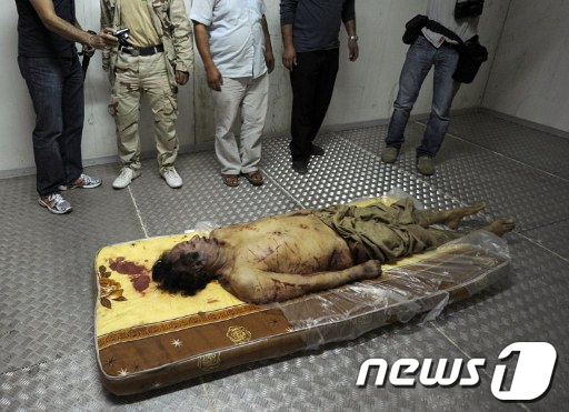 21일(현지시간) 카다피의 시신이 리비아 미스라타 교외에 있는 야채시장 냉동창고 매트리스 위에 놓여 있다. AFP  News1