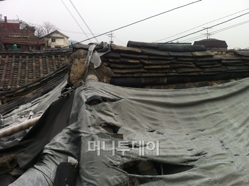 ↑ 재개발 예정지인 서울 종로구 옥인동의 한옥. 추위 방지를 위해 덮어둔 천들이 오래돼 찢어져 있다.