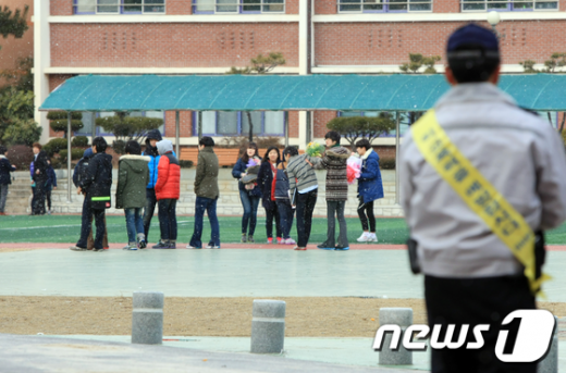 7일 졸업식이 열린 광주 동구 충장중학교에서 한 경찰관이 뒤풀이를 하는 학생들을 살펴보고 있다.  News1 김태성 기자
