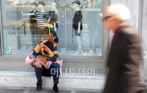 ↑ 그리스는 4년여에 걸친 경제불황으로 어려운 시기를 보내고 있다. 아테네 도심 스타디우 거리에 있는 한 상점 앞에 한 그리스인이 아기를 안은 채 동냥을 하고 있다. ⓒ사진=홍봉진 기자
