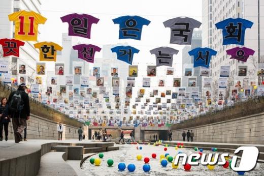 제19대 국회의원선거를 일주일 앞둔 4일 오전 서울 청계천에 투표참여 홍보를 위해 전시된 서울지역에 출마한 174명의 후보자 선거벽보 아래로 시민들이 지나가고 있다. 서울특별시선거관리위원회(위원장 이성보)는 청계천에서 서울지역 모든 후보자의 선거벽보와 특수제작된 티셔츠, 바람개비, 풍선 등을 설치해 유권자의 관심을 유도하고 투표참여 메시지를 전달할 것이라고 밝혔다.  News1 유승관 기자