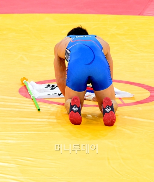 김현우가 7일 저녁(현지시간) 영국 엑셀 런던 노스아레나에서 열린 그레코로만형 66㎏급 결승전에서 금메달을 딴 후 태극기를 경기장에 놓은 후 큰절을 하고 있다. 김현우는 2004년 아테네올림픽 금메달리스트 정지현 이후 8년 만에 한국 레슬링에 금메달을 안겼다. 런던=올림픽사진공동취재단