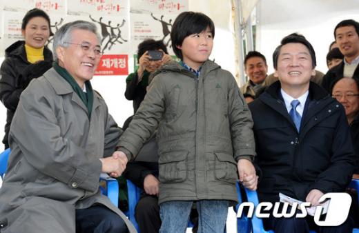 17일 오후 서울 영등포구 여의도공원에서 열린 한국노총 전국노동자대회에 참석한 문재인 민주통합당 후보와 안철수 무소속 후보가 인천에서 온 조융균 어린이와 함께 손을 잡고 있다. ⓒ사진=뉴스1제공, 박세연 기자