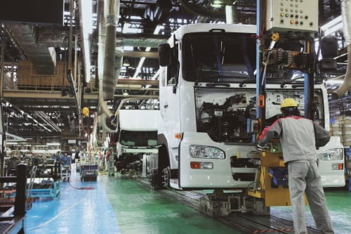 UD트럭 공장 조립라인에서 한 장인이 '큐온 카고'의 범퍼 부분을 차체에 붙이고 있다.