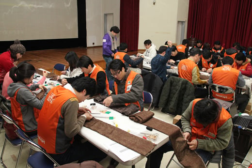 ↑지난 26일 호반건설 사내봉사단 '호반사랑나눔이' 소속 임직원 90여명이 서초구청에서 정기봉사활동의 일환으로 이지역 독거어르신 등에 전달할 '사랑의 목도리' 만들고 있다.. ⓒ사진=호반건설 제공