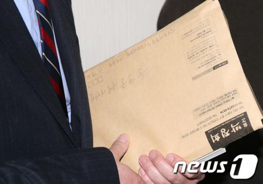 박근혜 대통령 당선인의 윤창중 수석대변인이 25일 오후 서울 여의도 당사에서 기자회견을 마친 후 "월간 박정희"라고 적힌 종이봉투를 손에 쥐고 있다. "월간 박정희"는 2008년 운영 등의 문제로 잠정 중단됐으나 최근 4년만에 다시 발행이 결정됐다. 2012.12.25/뉴스1  News1   양동욱 기자