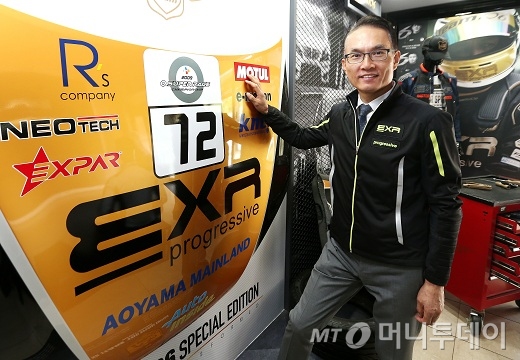 민복기 EXR코리아 대표이사가 후원중인 레이싱팀 현판앞에서 포즈를 취하고 있다./사진=홍봉진 기자