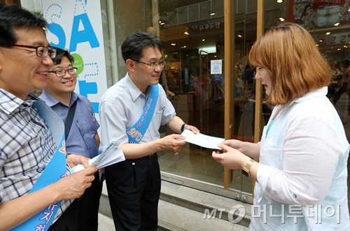변종립 에너지관리공단 이사장이 명동 TNGT를 방문해 직원에게 에너지절약 전단지를 나눠주고 있다. TNGT는 에너지 절약 스티커를 붙이고 가게 문을 닫은 채 영업중이었다. /사진=이동훈 기자