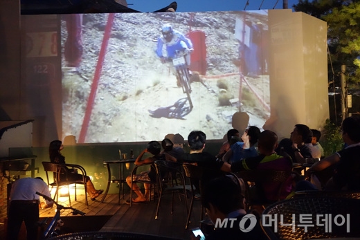 행사장 내 카페 테라스에 설치된 대형 스크린을 통해 산악자전거 다운힐 영상을 관람하고 있다./사진=이고운 기자