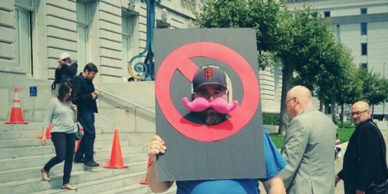 차량공유서비스 '리프트'의 상징인 분홍색 콧수염을 빗대어 시위를 벌이고 있는 택시 노조원. <사진출처:테크크런치>