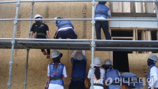 볼보건설기계 임직원과 가족들이 사랑의 집짓기 봉사활동에 참가해 벽재를 붙이고 있다. /진주(경남)=양영권 기자