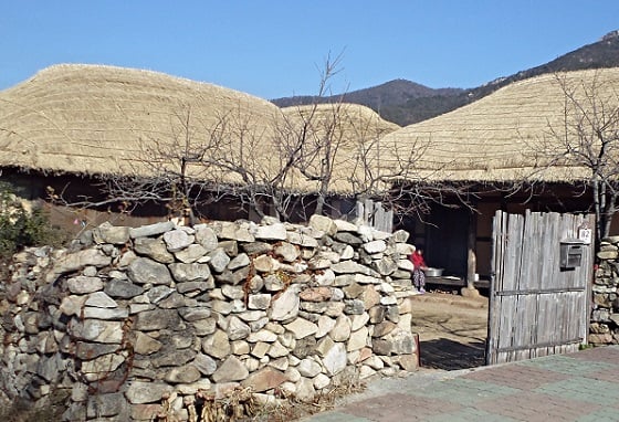 낙안읍성 밖에 있는 초가집. 열린 대문 사이로 할머니가 결명자 씨를 털어내는 모습이 보인다. / 사진=김유경기자